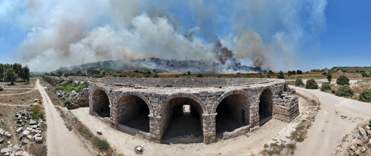 Flames are visible near the ancient stadium structure of the Perge archaeological site in Antalya, Türkiye, in a post shared on X by Aksu Mayor Isa Yildirim, July 25, 2025. (Photo via X/@aksuisayildirim)