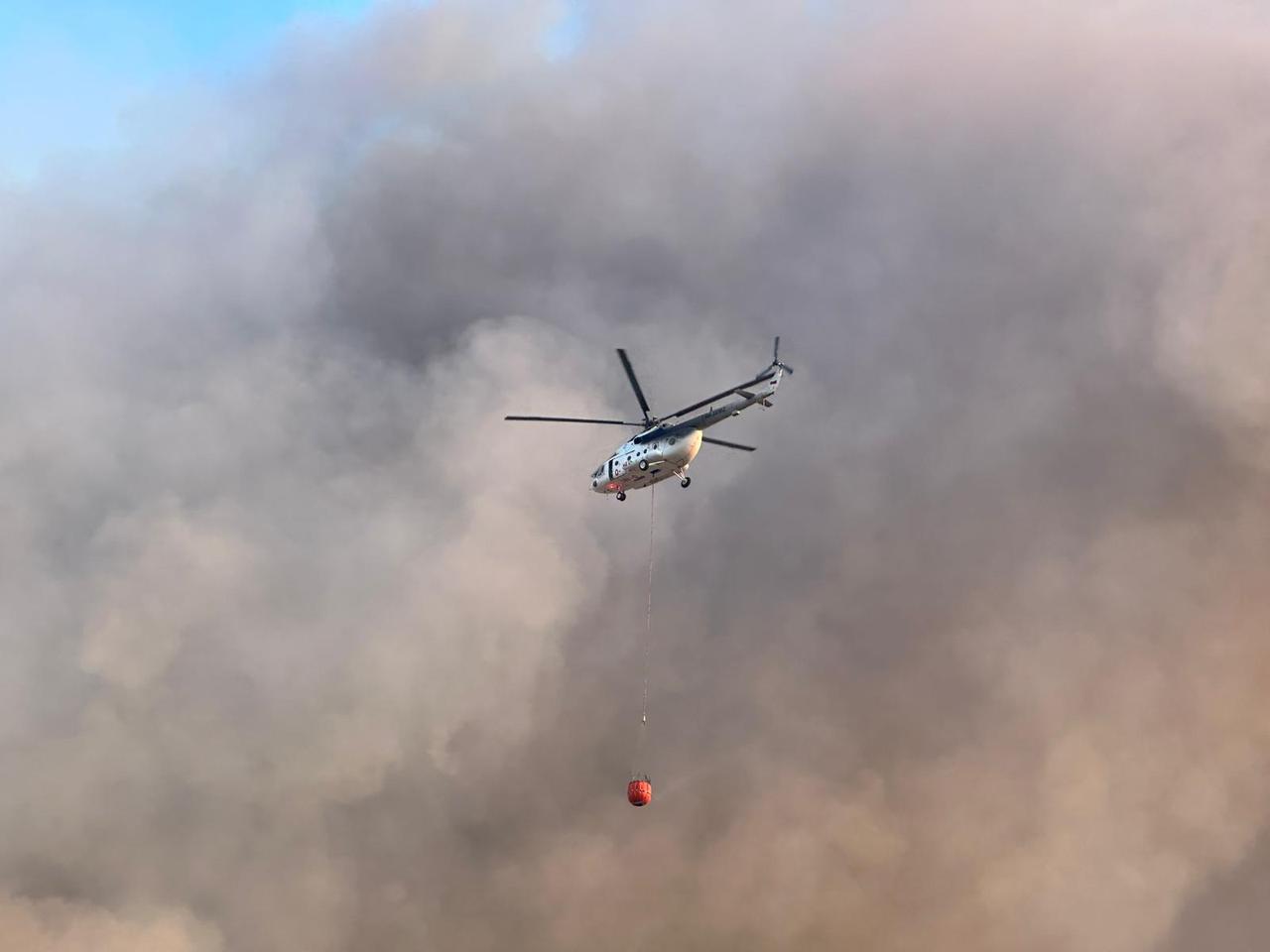 A firefighting helicopter flies over heavy smoke as efforts continue to extinguish a wildfire in the oak forest area of Sivasli district in Usak, Türkiye, July 26, 2025. (AA Photo)