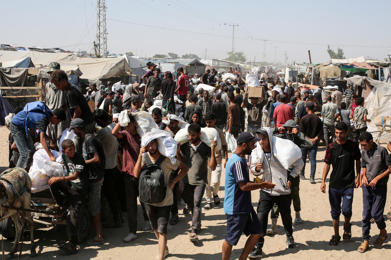People carry food parcels and bags in the al-Mawasi camp in Rafah in the southern Gaza Strip on July 27, 2025. (AFP Photo)