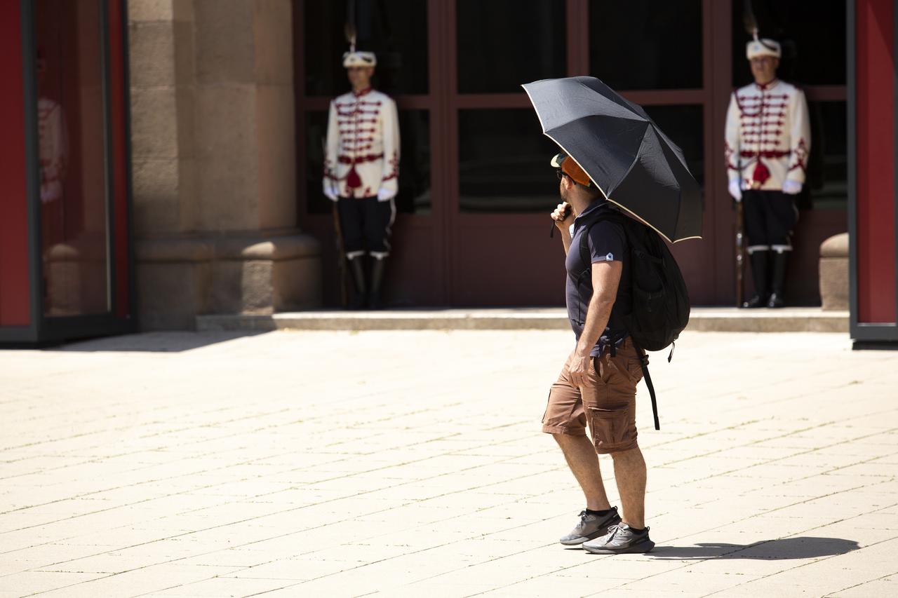 A man walks with an umbrella to protect himself from the sun as extreme heat grips Sofia as Bulgaria issues an orange code warning for hot weather, with maximum temperatures forecast between 36°C and 41°C and authorities urging caution for vulnerable populations, July 23, 2025. (AA Photo)