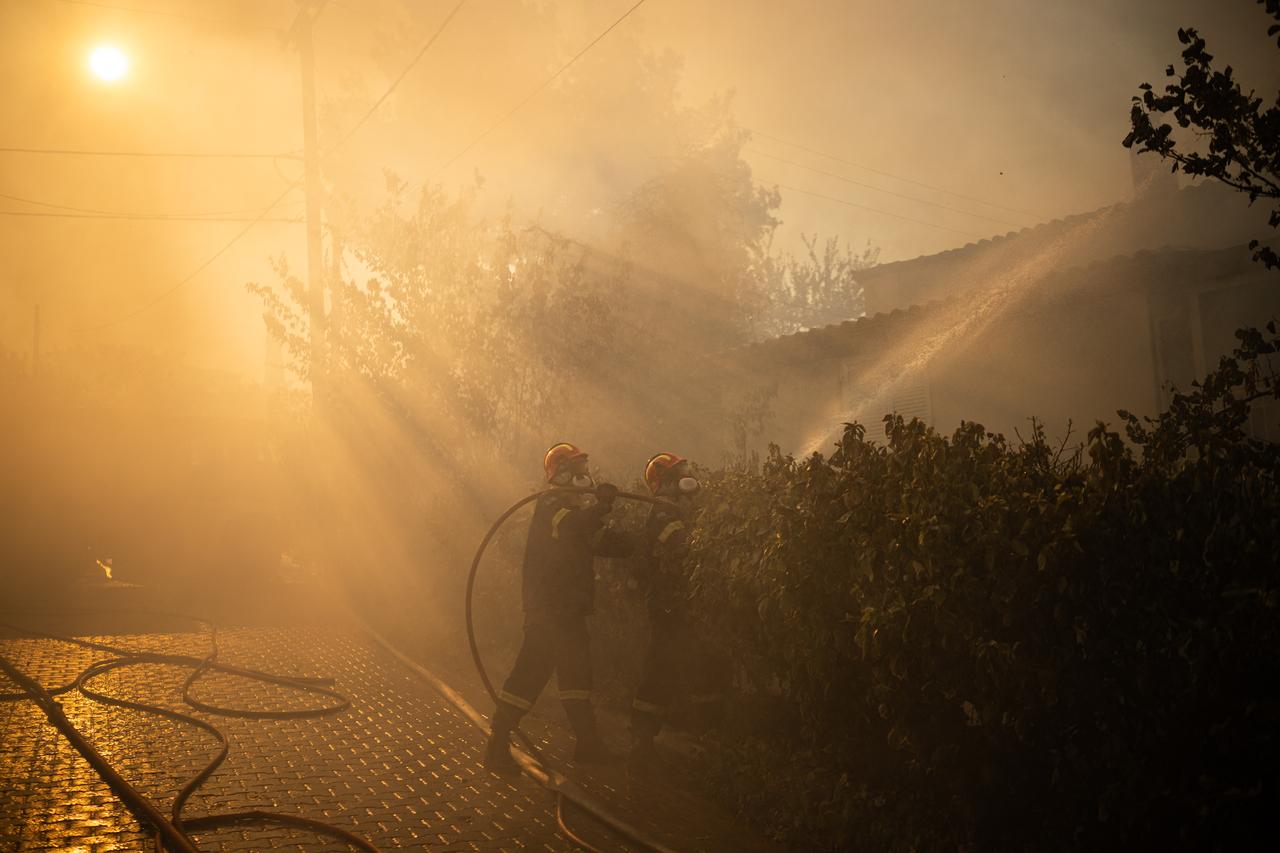 Firefighters try to extinguish the fire of a burning house during a wildfire in Kryoneri, near Athens in Greece, July 26, 2025. (AFP Photo)