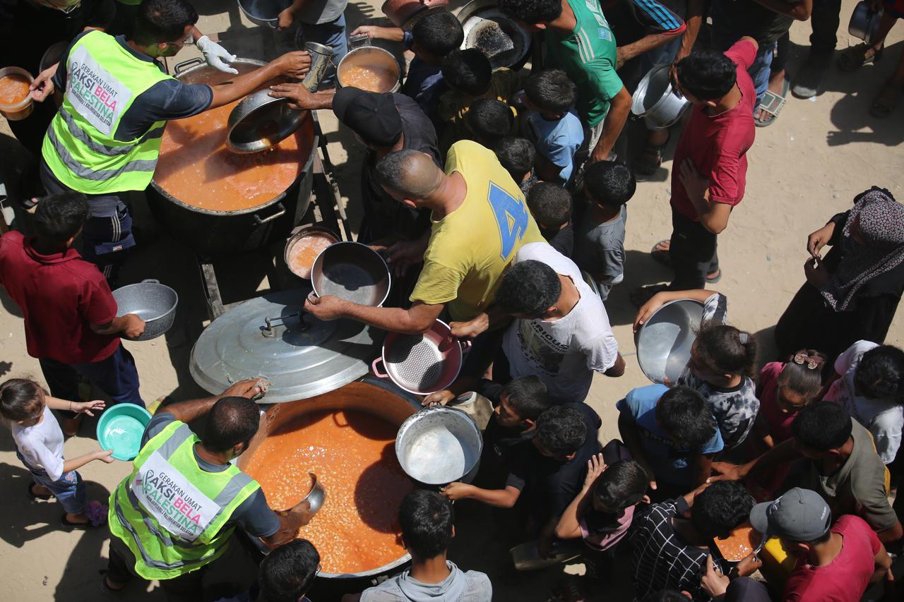 Palestinians carrying pots and containers gather as a charity distributes food in Az-Zawayda, Deir al-Balah, Gaza on July 29, 2025. (AA Photo)