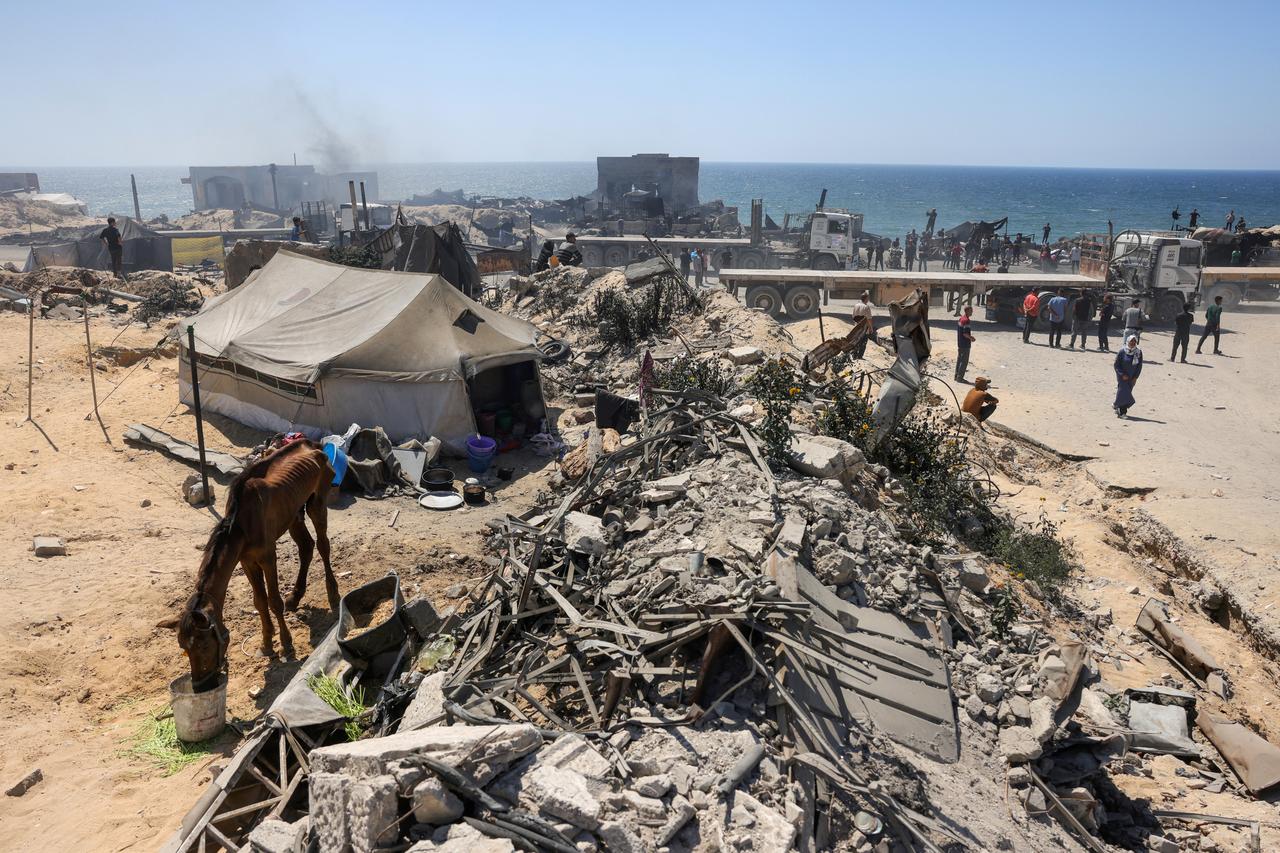 An emaciated horse drinks water at a displacement camp as trucks which brough aid drive back to leave the Gaza Strip from the Israeli-controlled Zikim crossing, west of Beit Lahia in the north of the besieged Palestinian territory on June 25, 2025. (AFP Photo)
