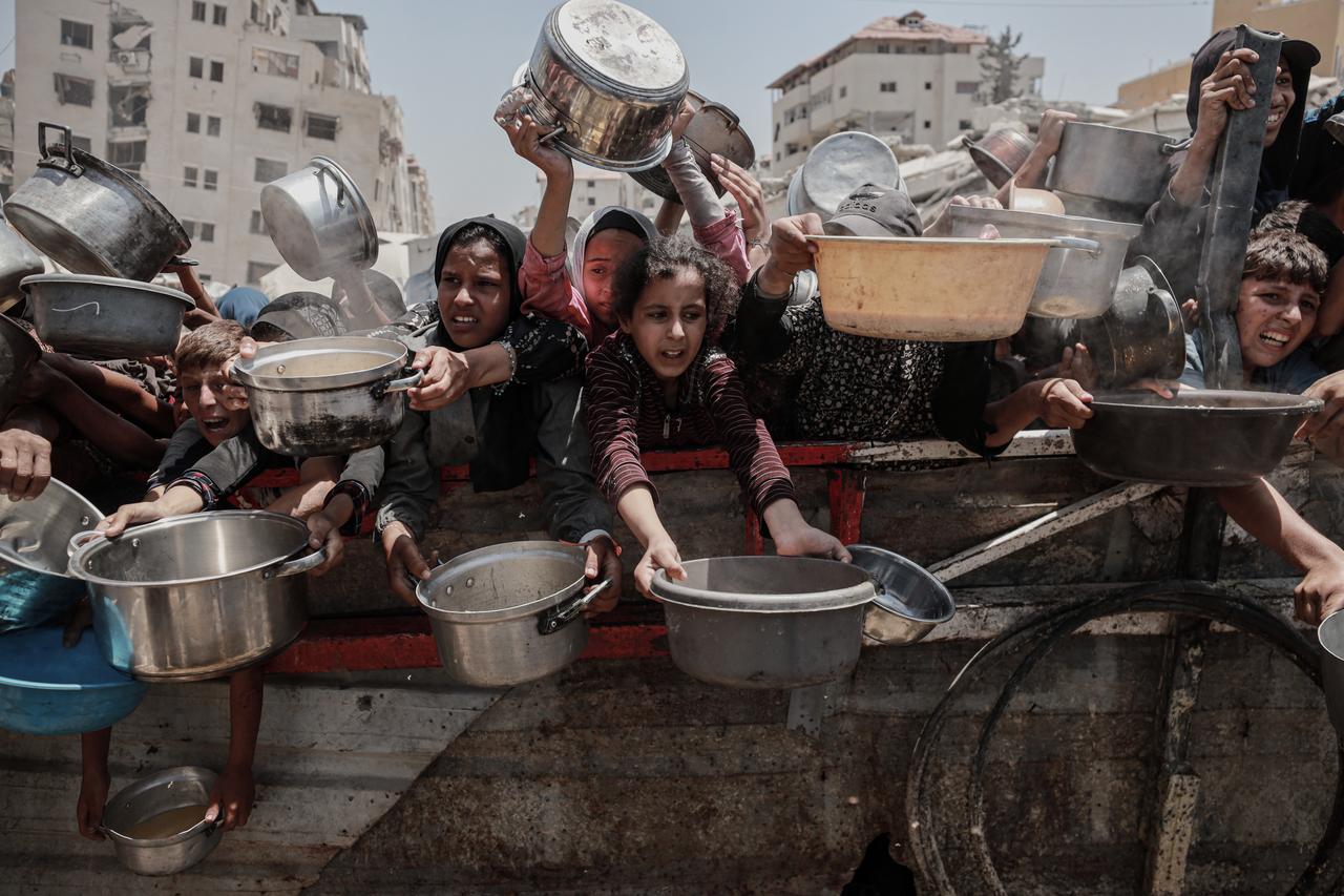 Palestinians, including children, who are struggling to access food due to Israel's blockade and ongoing attacks on the Gaza Strip, wait in line to receive hot meals distributed by the charity organization in Gaza City, Gaza, July 30, 2025. (AA Photo)
