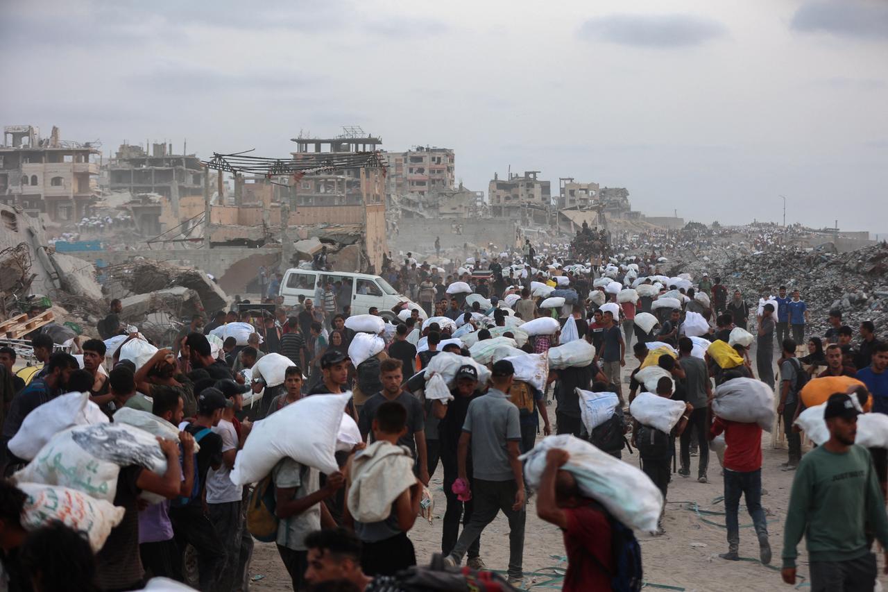 Palestinians bring back aid parcels they managed to procure as they walk on a coastal path west of Beit Lahia on July 29, 2025. (AFP Photo)