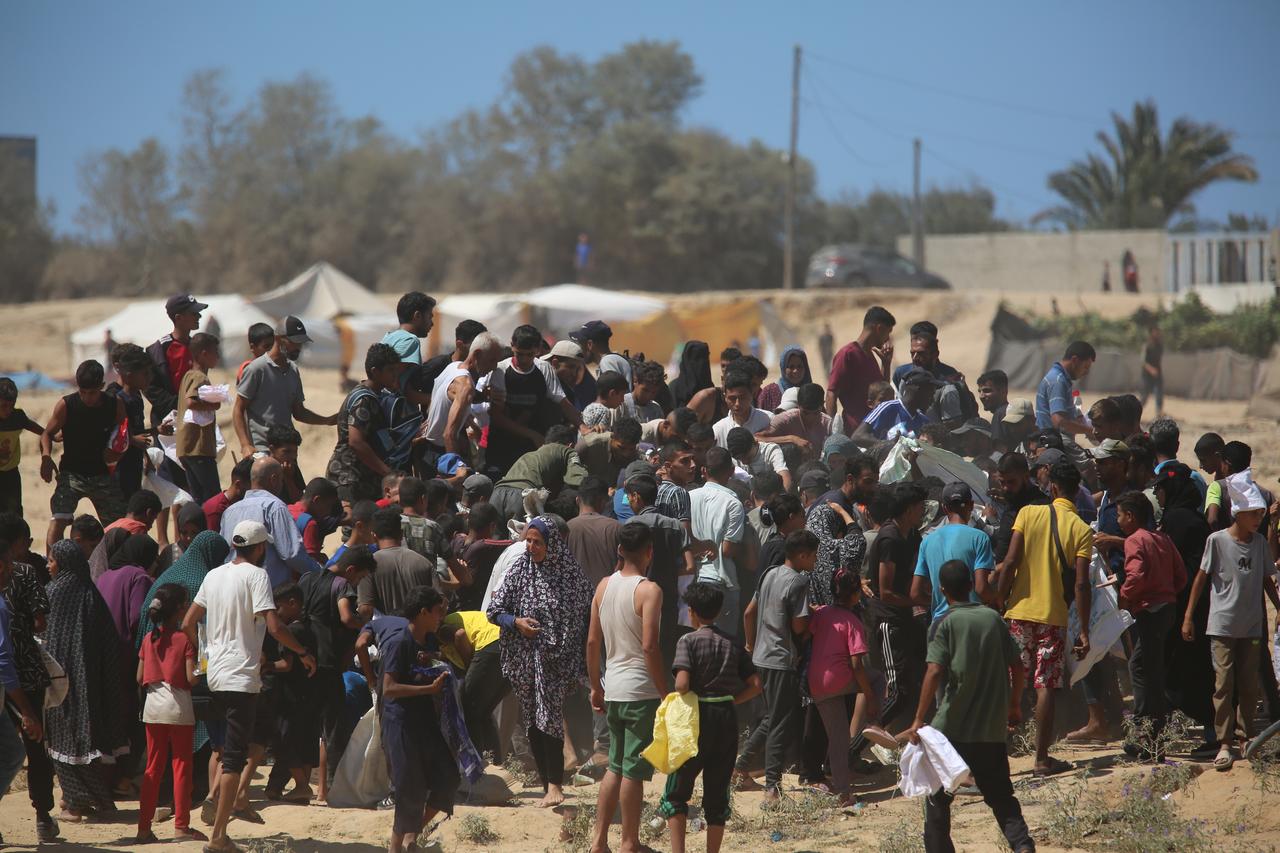 Palestinians rush to collect humanitarian aid dropped by parachute in the Al-Zawaida area of Deir al-Balah, Gaza Strip, on July 31, 2025. (AA Photo)