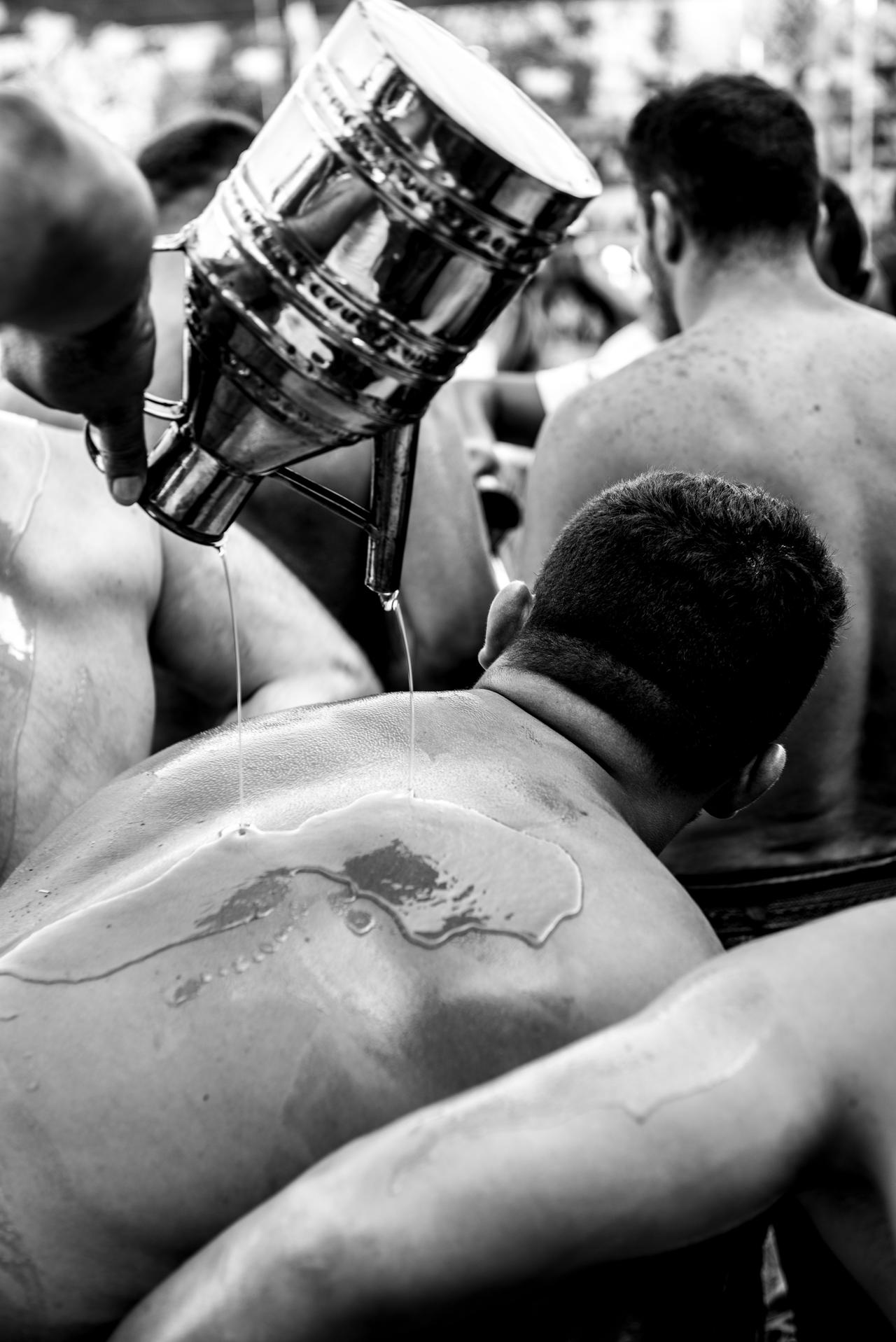 Wrestler is pouring oil himself before the competition. (Adobe Stock Photo)