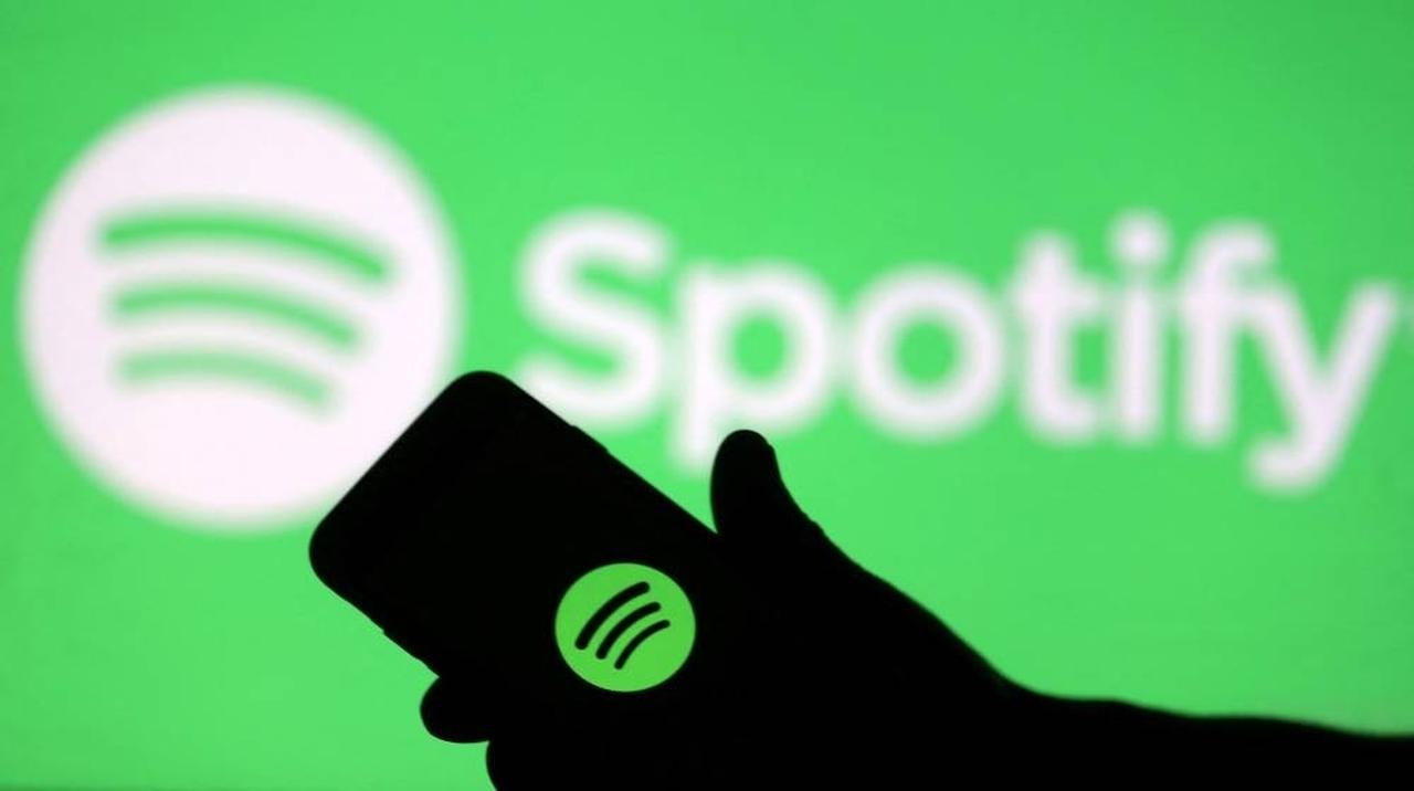 Hand silhouette holding a phone with a Spotify logo on it,  in front of a Spotify logo, accessed on July 4, 2025. (AFP Photo)