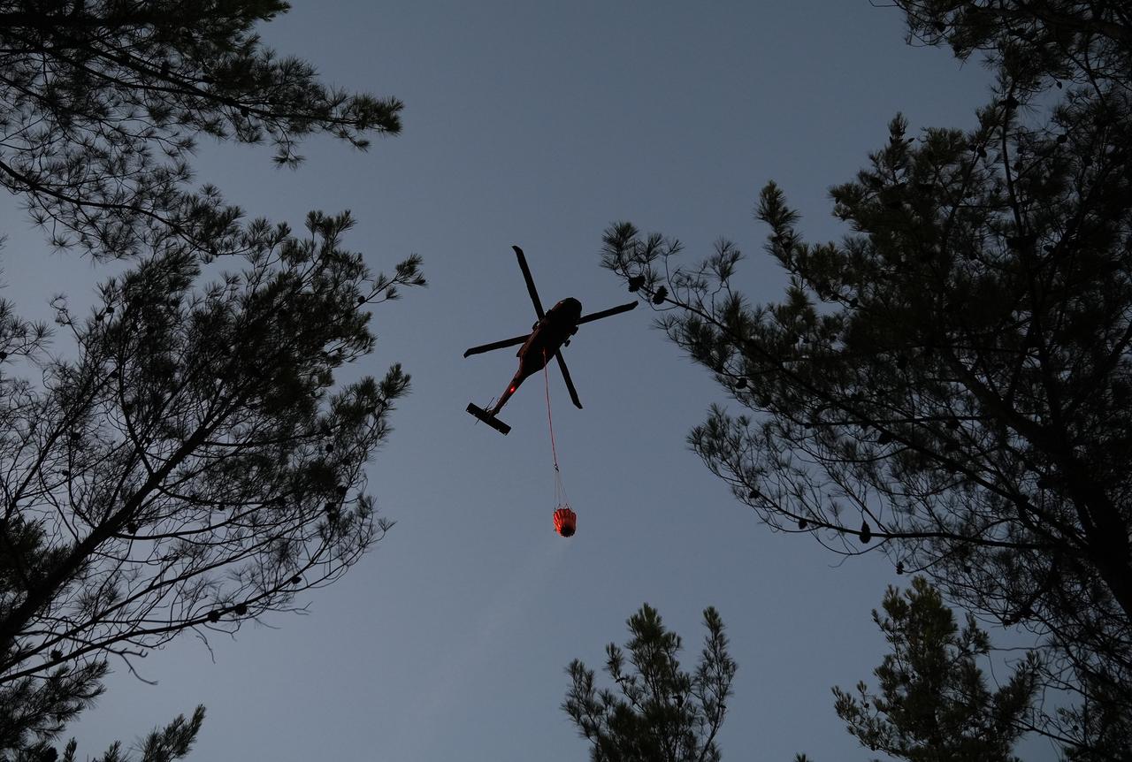 A helicopter carries water to extinguish fire as air and land intervention continues against the fire that broke out in the forest area in Buca district of Izmir, Türkiye on July 03, 2025. (AA Photo)