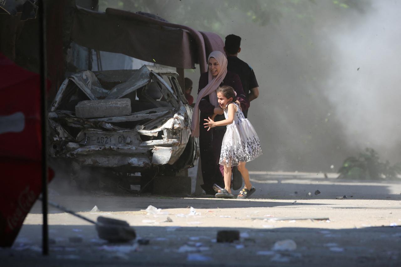 A Palestinian mother and her daughter rush for cover during an Israeli strike in the Al-Bureij camp in the central Gaza Strip on July 4, 2025. (AFP Photo)