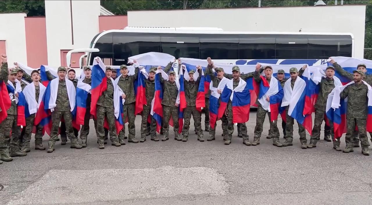 A screen grab taken from a video shows Russian military personnel being seen with national flags draped over their shoulders after returning Russia on July 4, 2025. (Russian Defense Ministry / Handout)