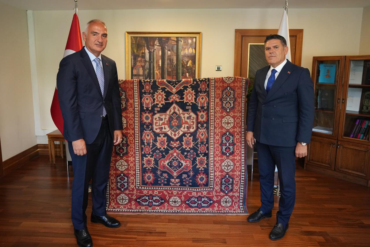 Minister of Culture and Tourism Mehmet Nuri Ersoy (L) and Italian national Adrian Stefan Ionescu (R), who had acquired the piece from a private collection, pose with the approximately 500-year-old Usak carpet (C) during the handover ceremony, 6 July 2025. (AA Photo)