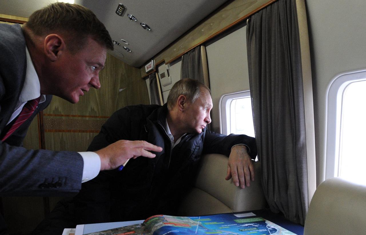 Russian President Vladimir Putin (C), accompanied with head of the Federal Road Agency Roman Starovoyt, inspects the site of the under-construction bridge across the Kerch strait, which will link Russia and the Crimean peninsula, from onboard a helicopter, on March 18, 2016. (Sputnik / AFP Photo)