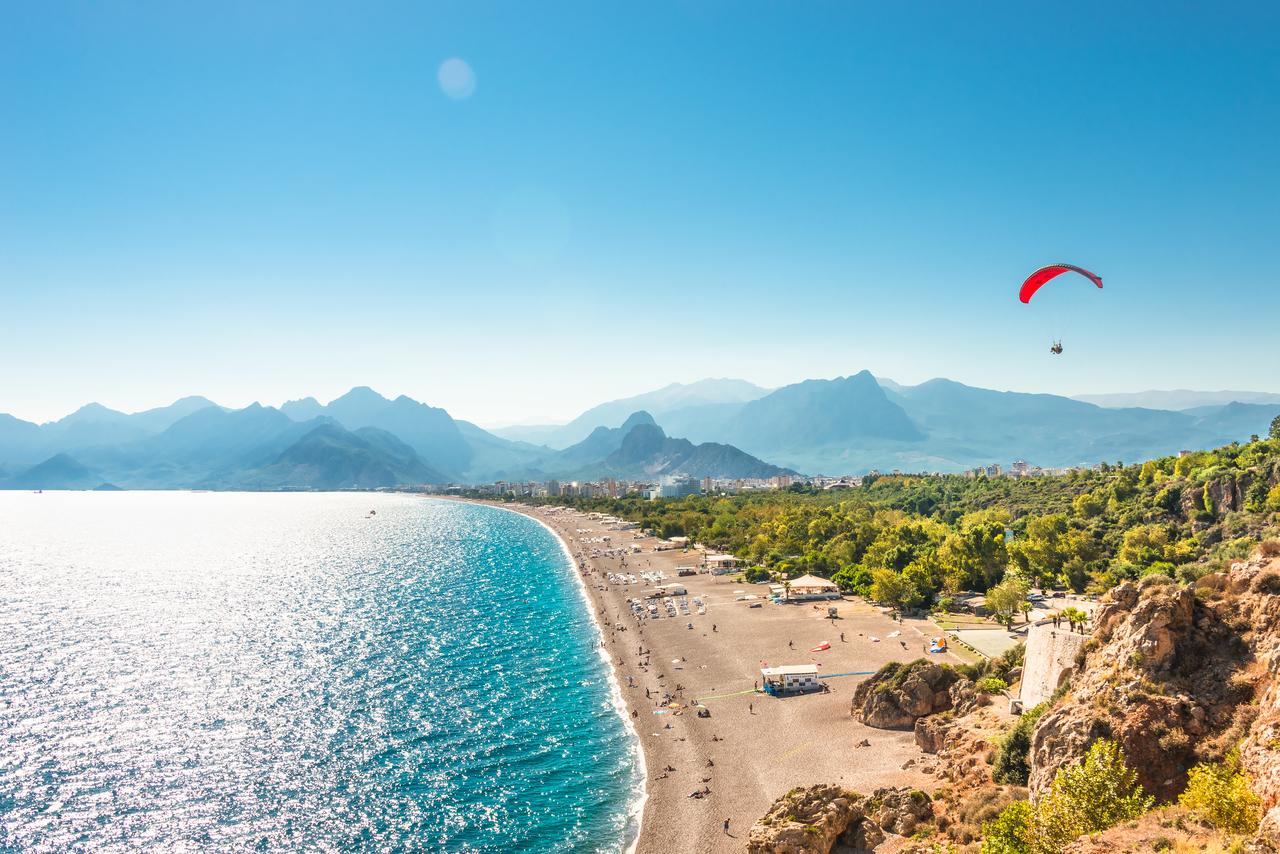 Panoramic bird view of Antalya and Mediterranean seacoast and beach with a paraglider, Antalya, Türkiye. (Adobe Stock Photo)