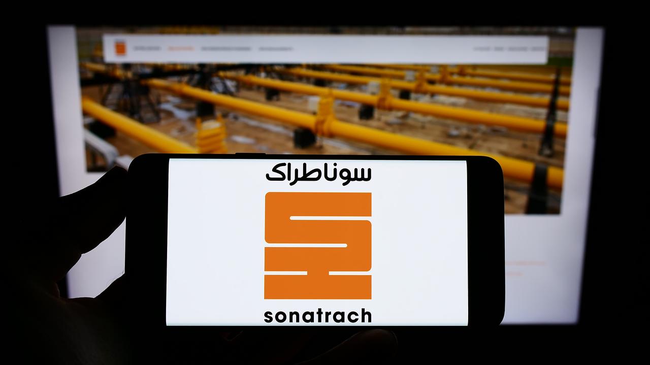 Photo illustration shows a person holding a smartphone displaying the logo of Algerian state-owned oil and gas company Sonatrach in Stuttgart, Germany, on January 12, 2022. (Adobe Stock Photo)