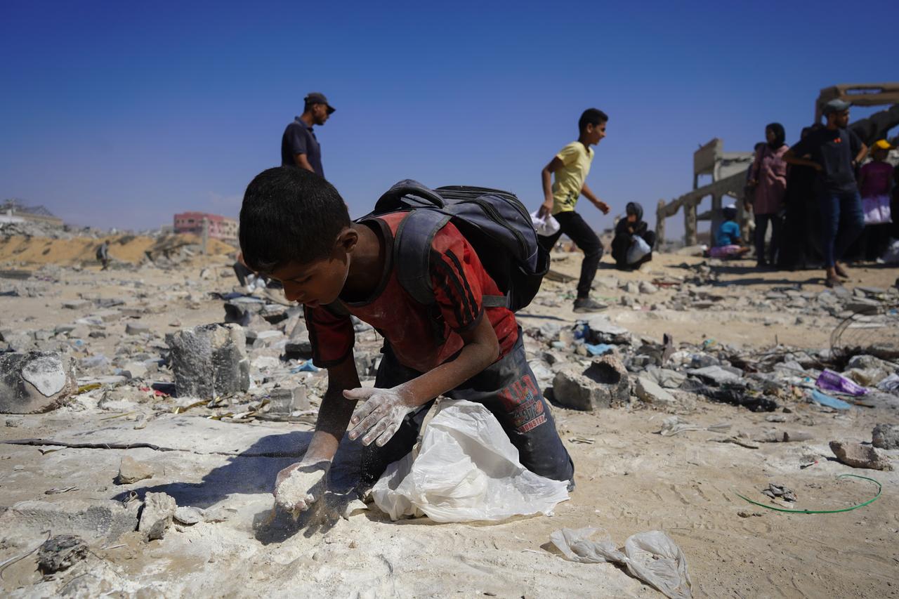 A child tries to collect flour on ground as Palestinians, struggling with hunger, receive limited amount of flour at humanitarian aid distribution point at Zikim border crossing in Gaza, August 1, 2025. (AA Photo)