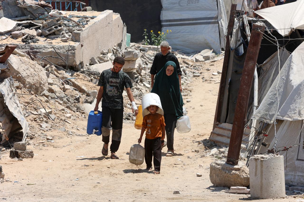 A Palestinian child covers his head with a bucket as he and others carry gallons of clear water from a distribution point in Gaza City, August 1, 2025. (AFP Photo)