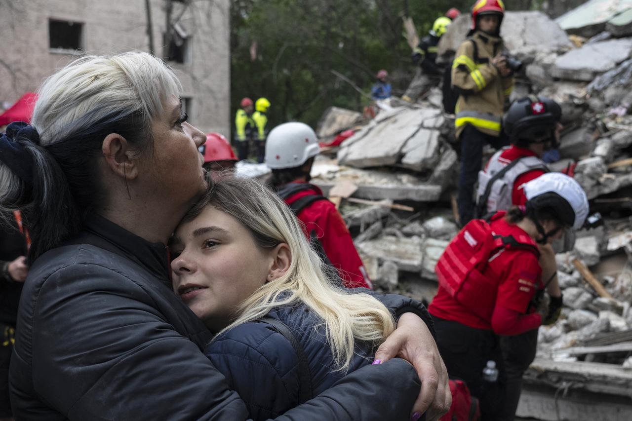 Local residents comfort each other as Ukrainian rescuers work among the rubble of a destroyed residential building following an air attack in Kyiv on July 31, 2025. (AFP Photo)