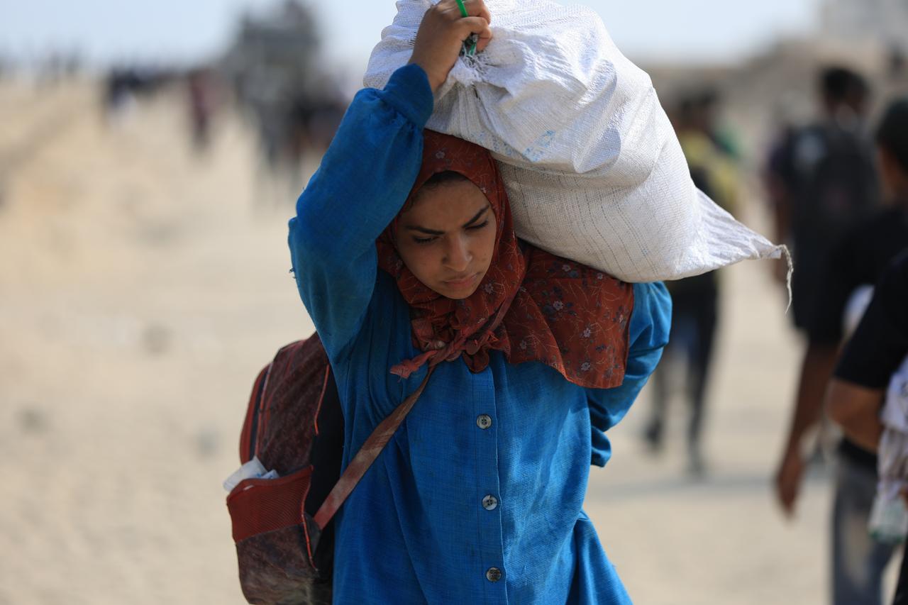 Palestinian woman carrying bag of flour as Palestinians struggling with hunger in the Gaza Strip rush to a humanitarian aid distribution point near the Zikim Crossing in northwest Gaza, August 10, 2025. (AA photo)