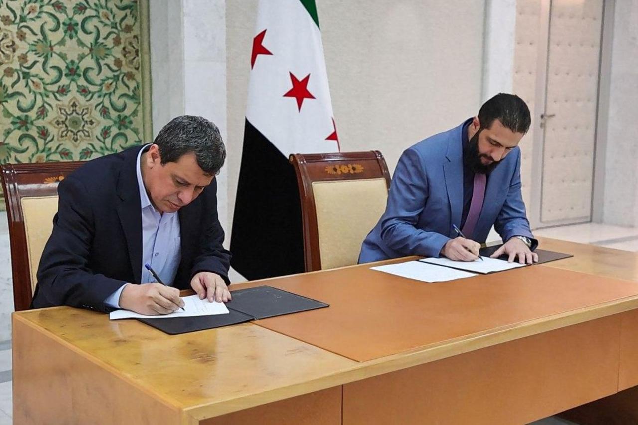 A handout picture released by the official Syrian Arab News Agency (SANA) shows Syrias interim president Ahmed al-Sharaa (R) and terrorist YPG-dominated SDF ringleader Mazloum Abdi signing an agreement, to integrate the institutions of the semi-autonomous Kurdish administration in the northeast into the national government, in the Syrian capital Damascus on March 10, 2025. (AFP Photo)