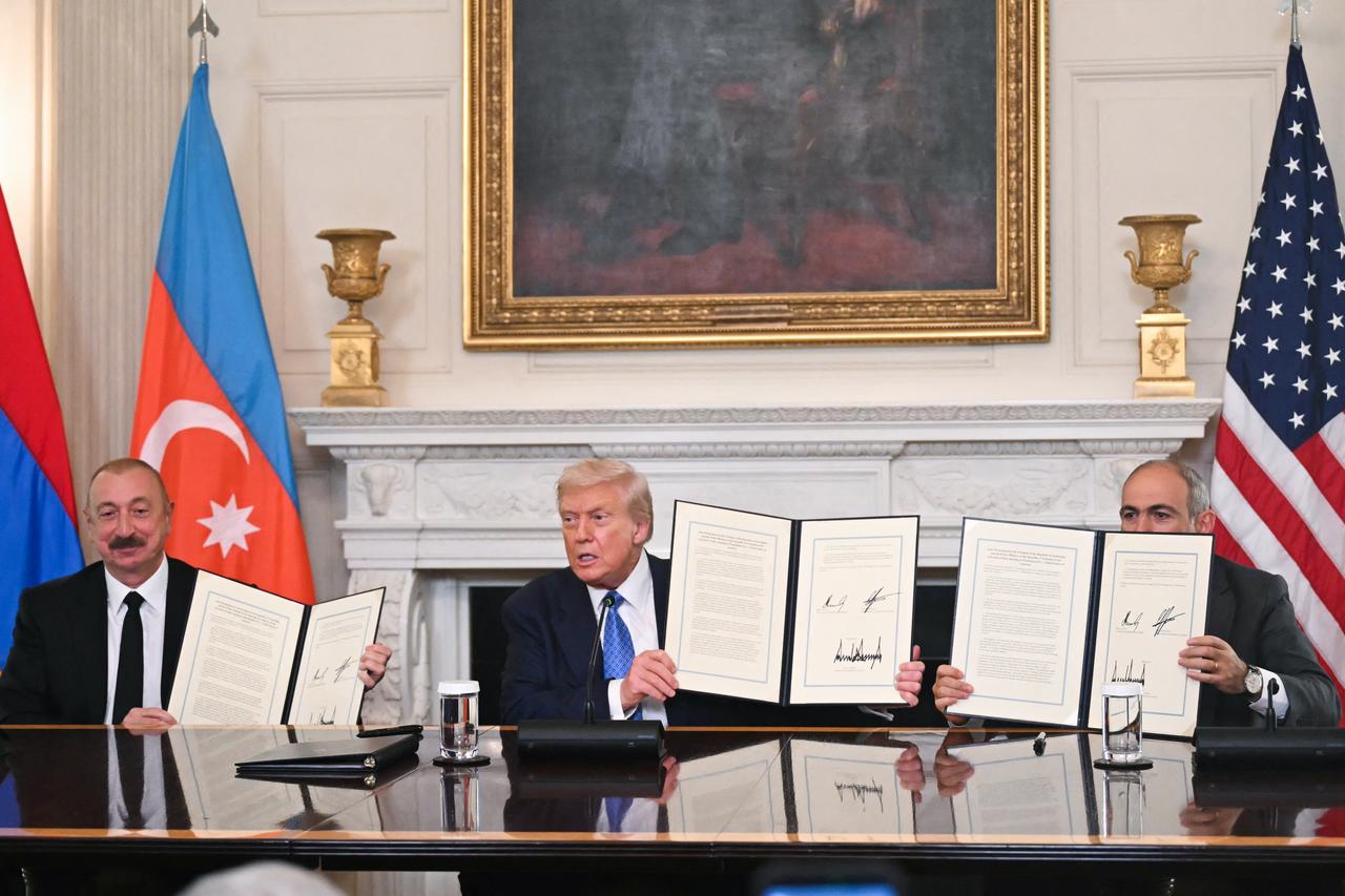US President Donald Trump (C), Azerbaijani President Ilham Aliyev (L) and Armenian Prime Minister Nikol Pashinyan display the agreement they signed in the State Dining Room of the White House in Washington, DC on August 8, 2025. (AFP Photo)
