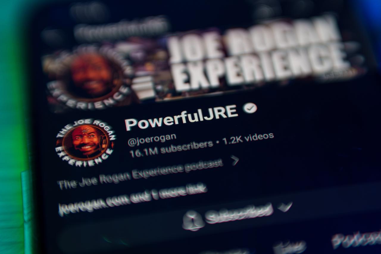 A smartphone screen displays the popular ‘Joe Rogan Experience’ podcast on YouTube. (Adobe Stock Photo)