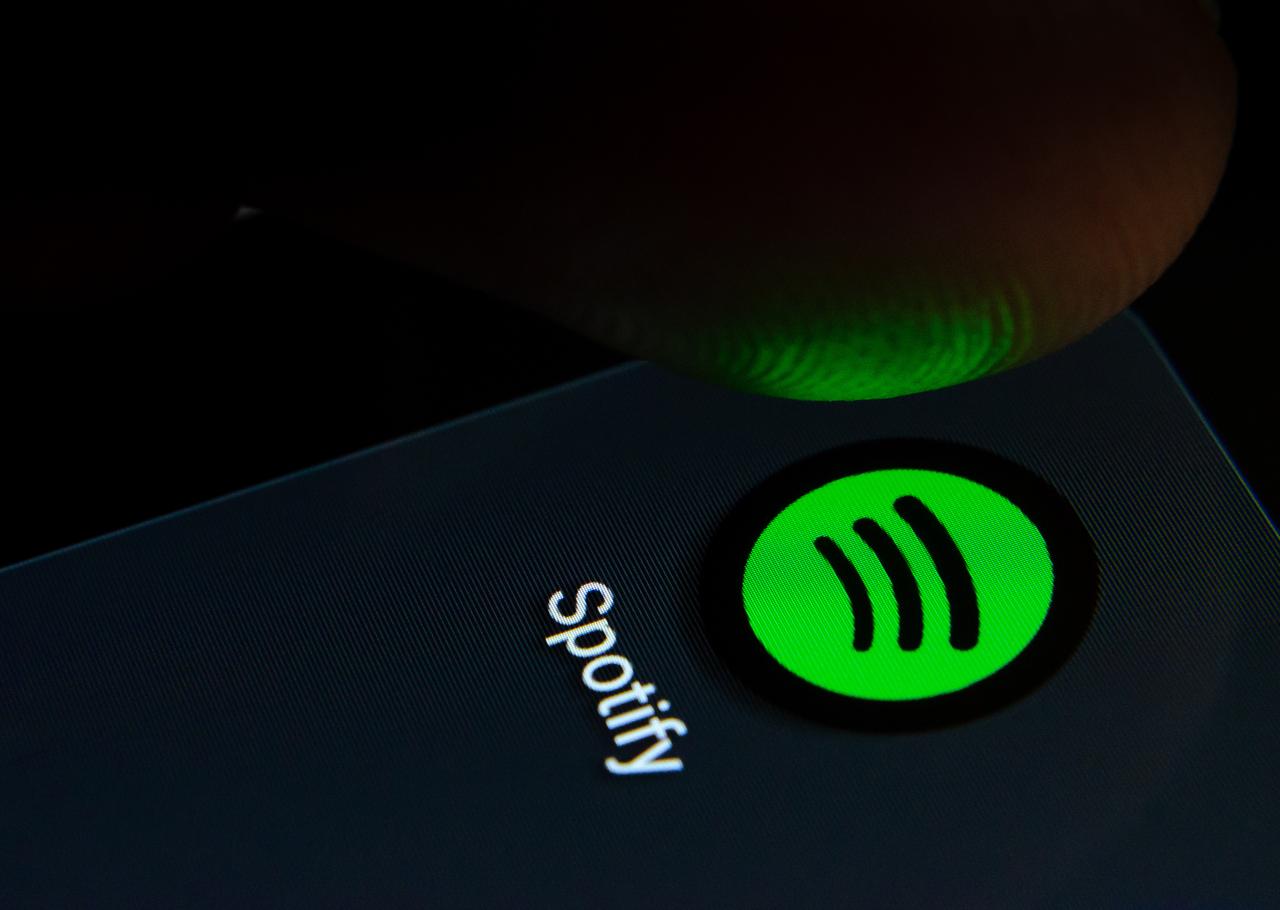 Spotify app icon on the smartphone screen with visible pixels and the finger about to launch it in Staffordshire, United Kingdom on July 28 2019. (Adobe Stock Photo)