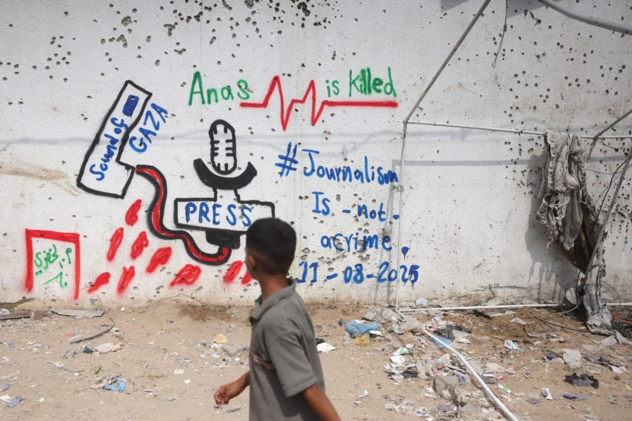 A Palestinian boy looks at graffiti on the wall at the site where a deadly Israeli strike destroyed an Al Jazeera tent and killed six journalists at the Al-Shifa Hospital in Gaza City on August 12, 2025. (AFP photo )