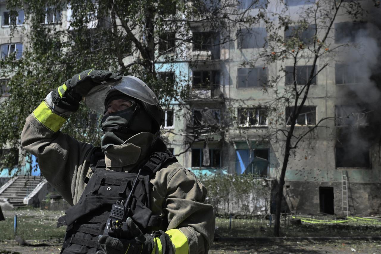 An Ukrainian firefighter checks the sky for enemy drones at the site of a Russian drone strike in the town of Bilozerske, Donetsk region on August 10, 2025. (AFP Photo)