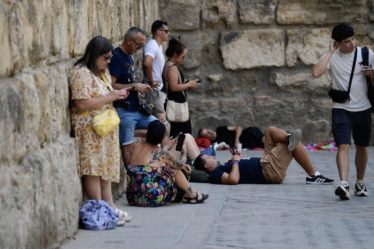 People use their smartphone as they protect themselves from the heat under the shade of a tree during the extreme heatwave in Seville, August 12, 2025. (AFP Photo)
