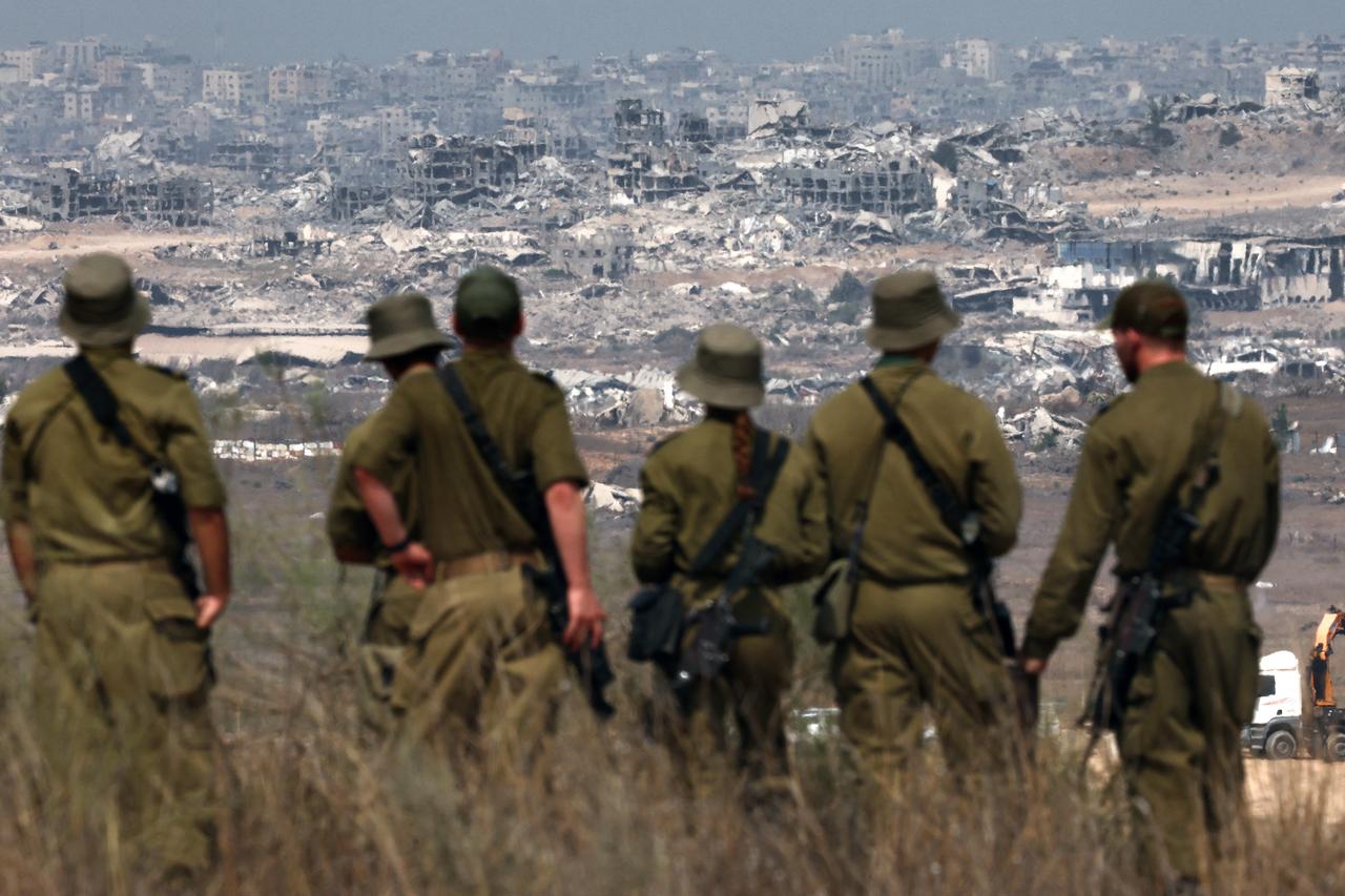 Israeli army soldiers look at destroyed buildings in the Gaza Strip as they stand on the border with the Palestinian territory, on August 13, 2025. (AFP Photo)