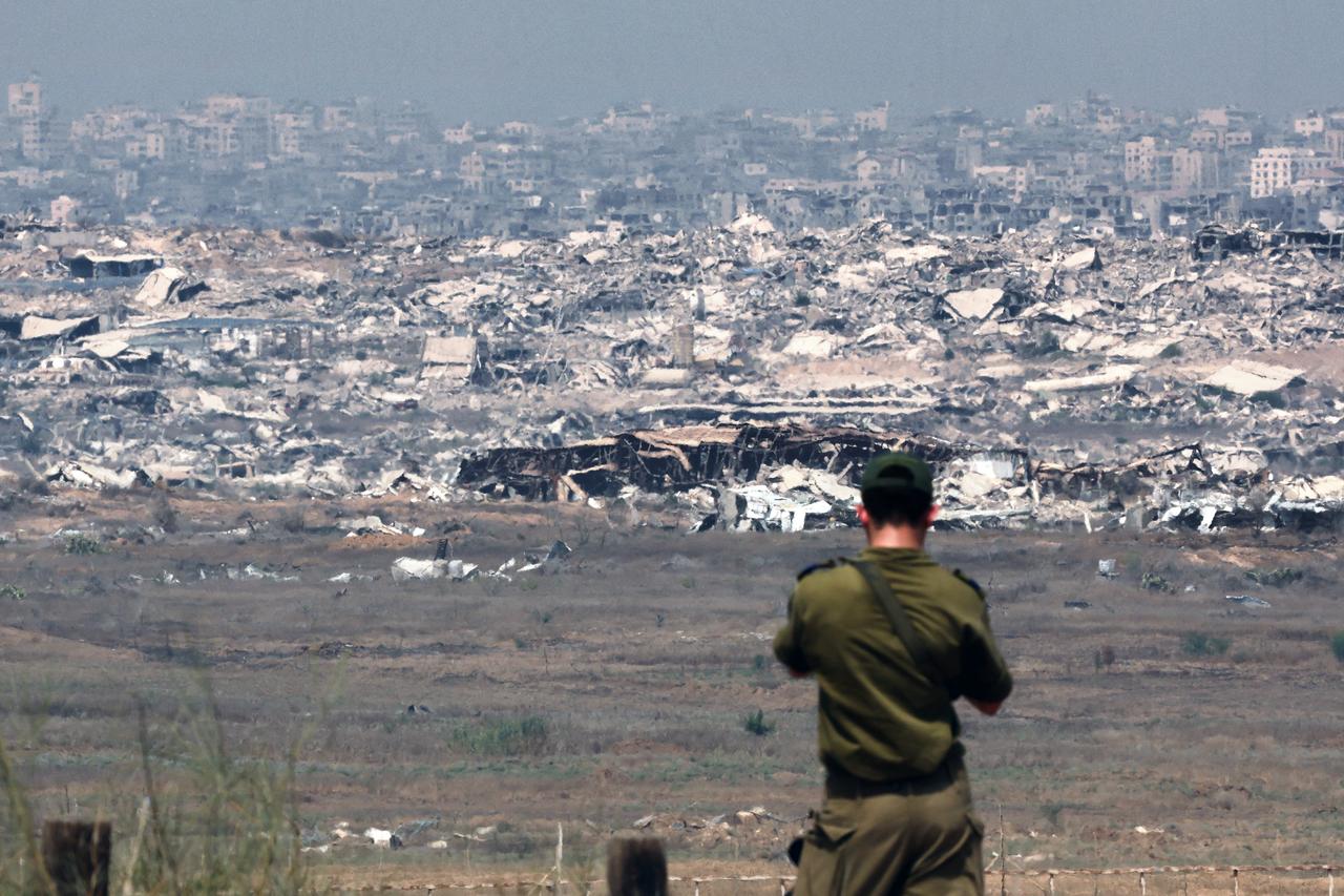 An Israeli army soldier looks at destroyed buildings in the Gaza Strip as troops stand on the border with the Palestinian territory, on August 13, 2025. (AFP Photo)
