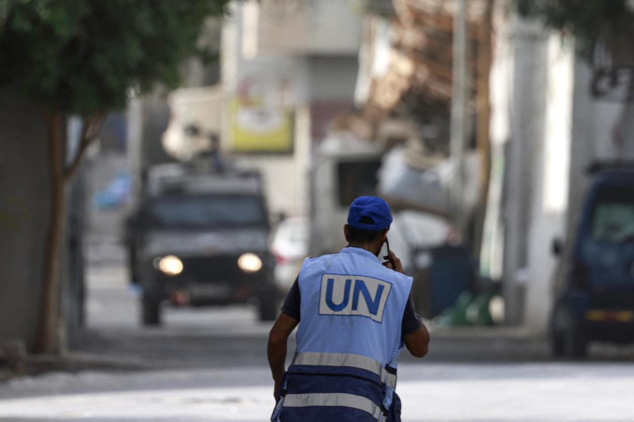 A man wearing a UN vest uses his phone as Israeli soldiers arrive for a raid at the Balata refugee camp east of Nablus city in the occupied West Bank, Palestine, August 11, 2025. (AFP Photo)