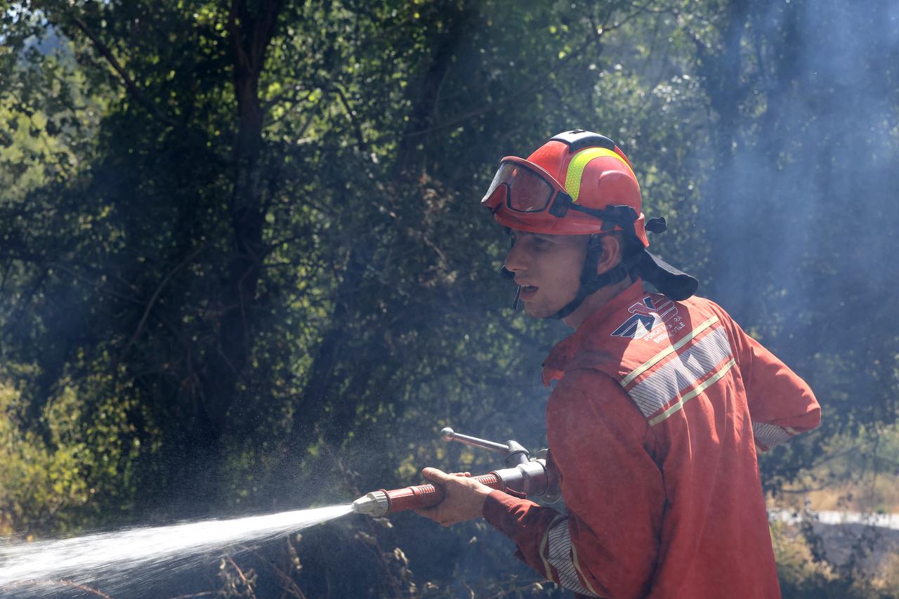 A firefighter sprays water on a wildfire close to the Blue Eye national park, near Sarande, south Albania, August 12, 2025. (AFP Photo)