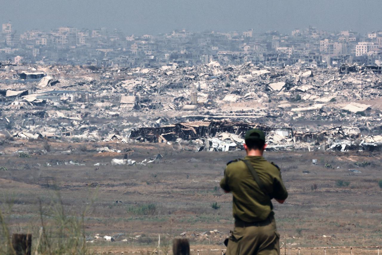 An Israeli army soldier looks at destroyed buildings in the Gaza Strip as troops stand on the border with the Palestinian territory, on August 13, 2025. (AFP Photo)