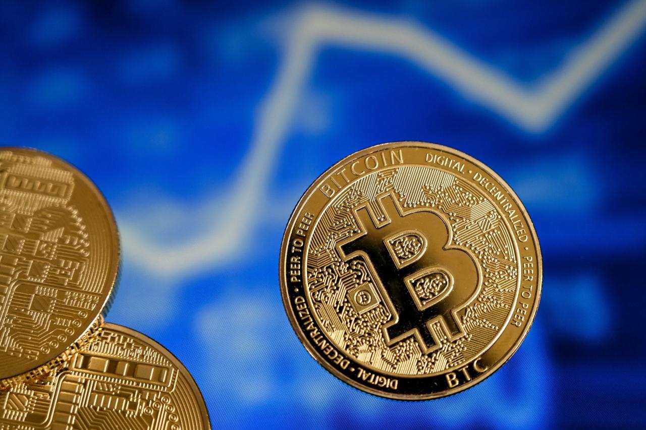 Photo illustration shows a Bitcoin token displayed against a digital chart background. (IHA Photo)