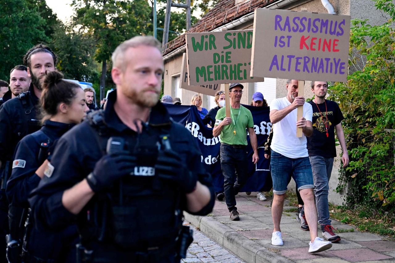 Police officers walk alongside demonstrators holding signs that read  Racism is no alternative  near the election event venue of the far-right Alternative for Germany (AfD) party, Potsdam, Germany, September 22, 2024. (AFP Photo)
