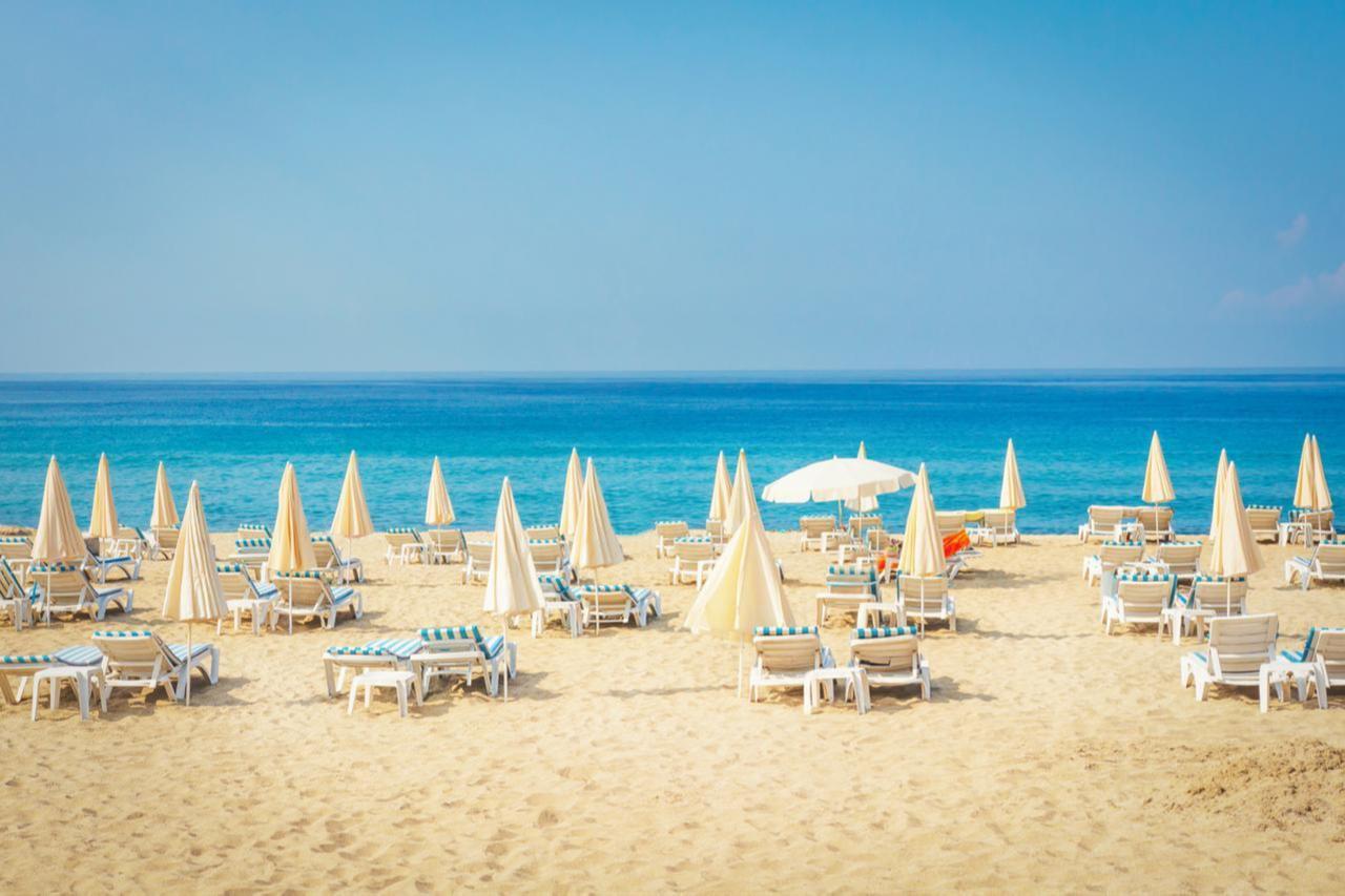 Sun loungers and umbrellas arranged on a sandy beach in Antalya, Türkiye. (Adobe Stock Photo)