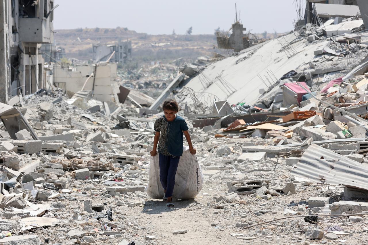 A Palestinian girl transports salvaged items next to destroyed buildings in the al-Tuffah neighbourhood of Gaza City on August 14, 2025. (AFP Photo9