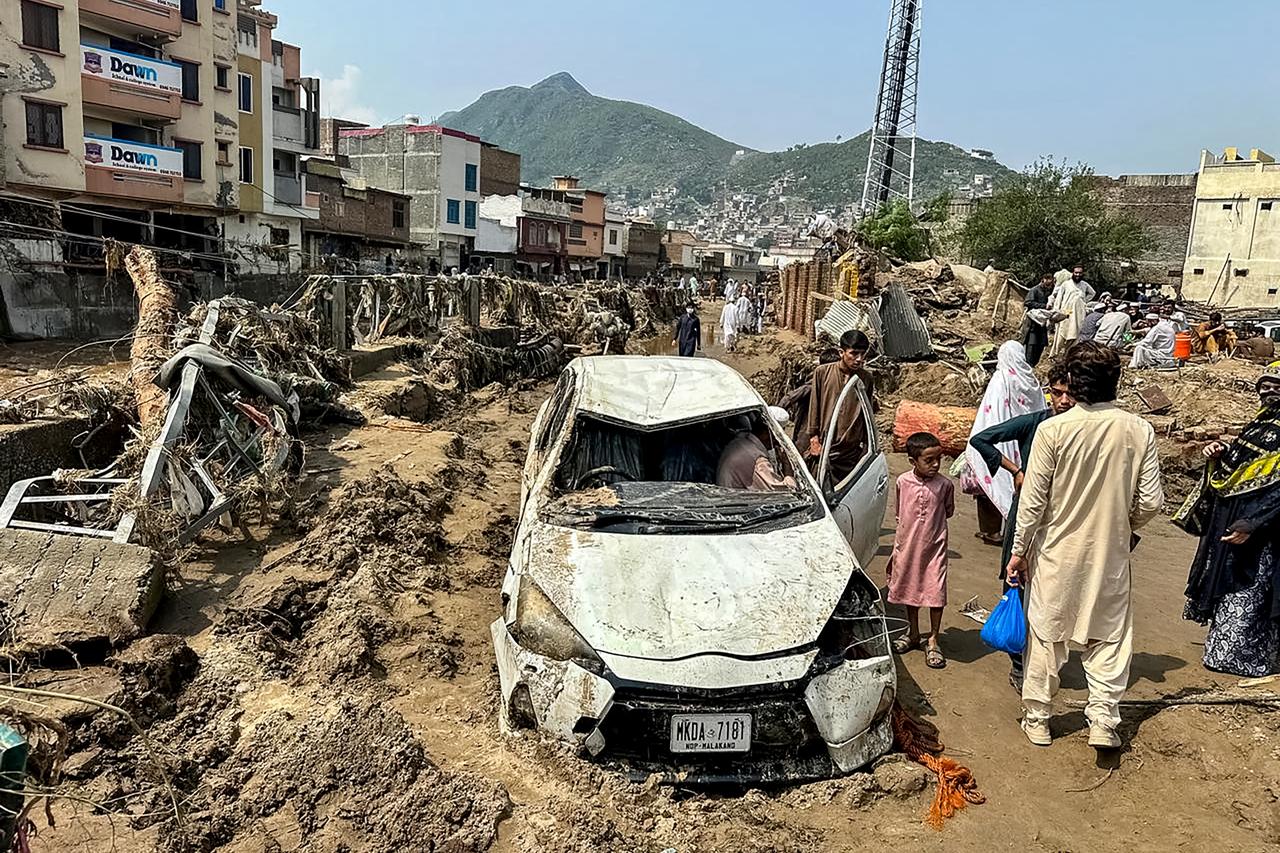 People gather near a damaged vehicle and scattered debris after the road washed out following a flash flood in Mingora, Khyber Pakhtunkhwa, Pakistan on August 16, 2025. (AFP Photo)