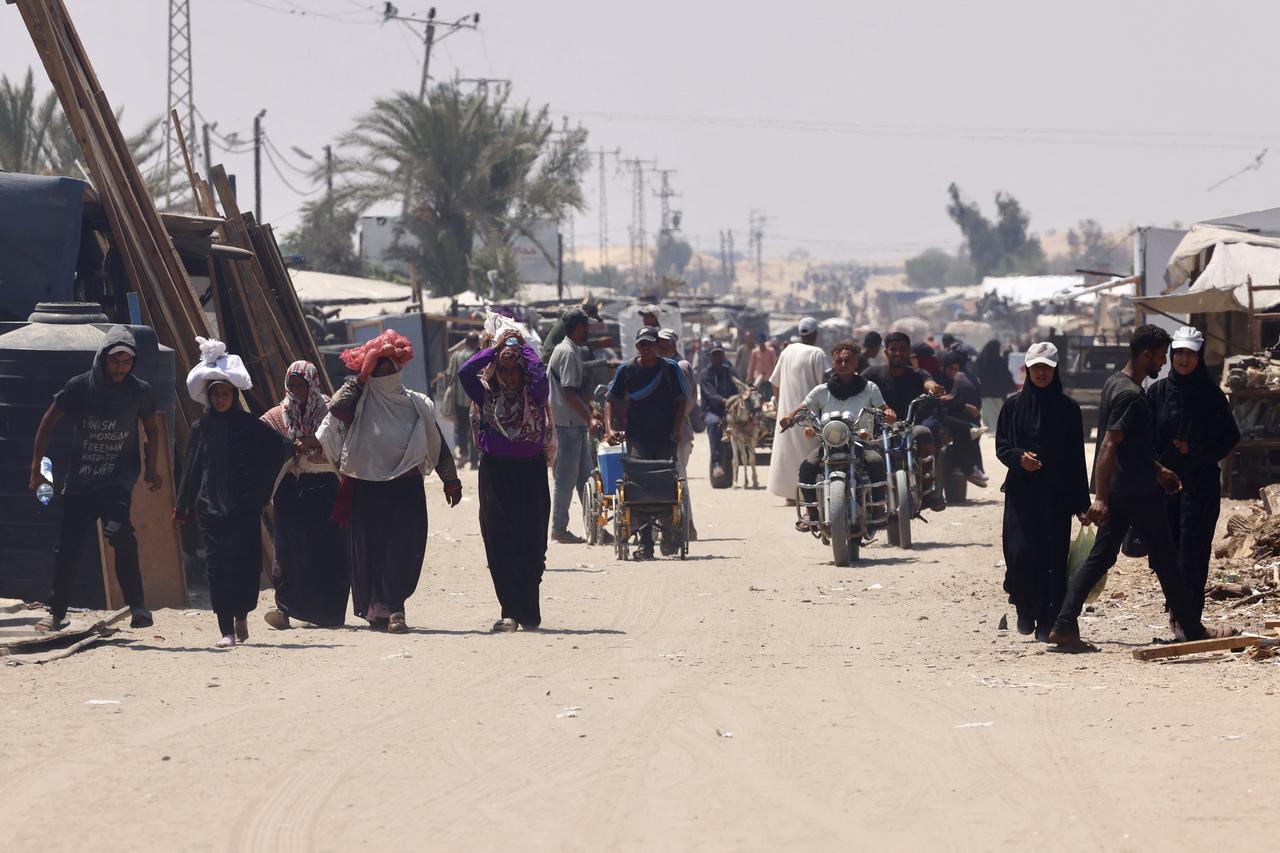 Palestinians carry humanitarian aid, they gathered after an aid drop, as they walk in the Mawasi area of Rafah in the southern Gaza Strip on August 18, 2025. (AFP Photo)