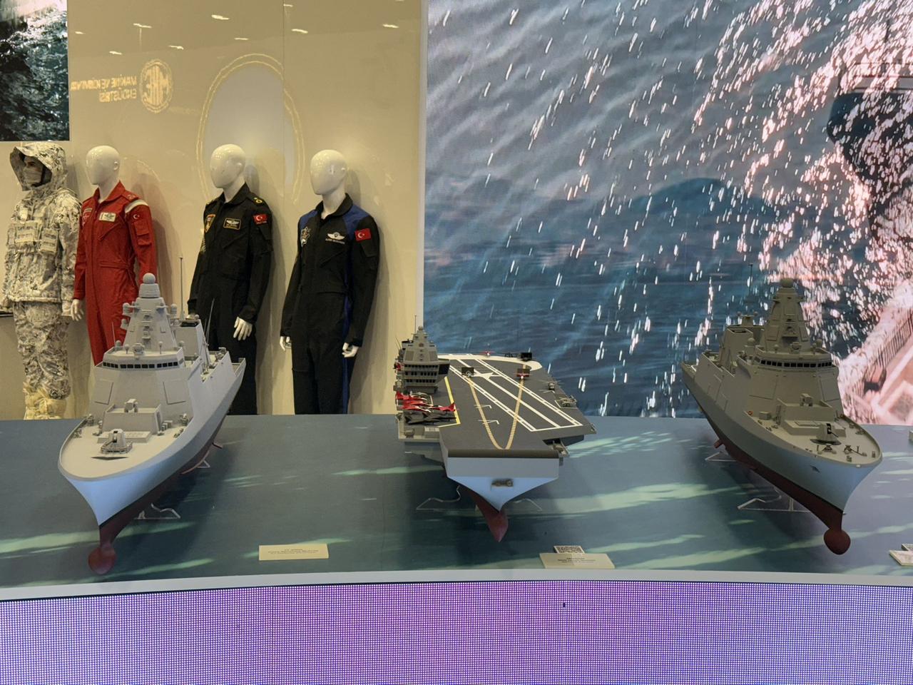 Türkiye's MUGEM aircraft carrier (C) and TF-2000 old (R) and new (L) models at IDEF 2025. (Photo via X@TayfunOzberk)