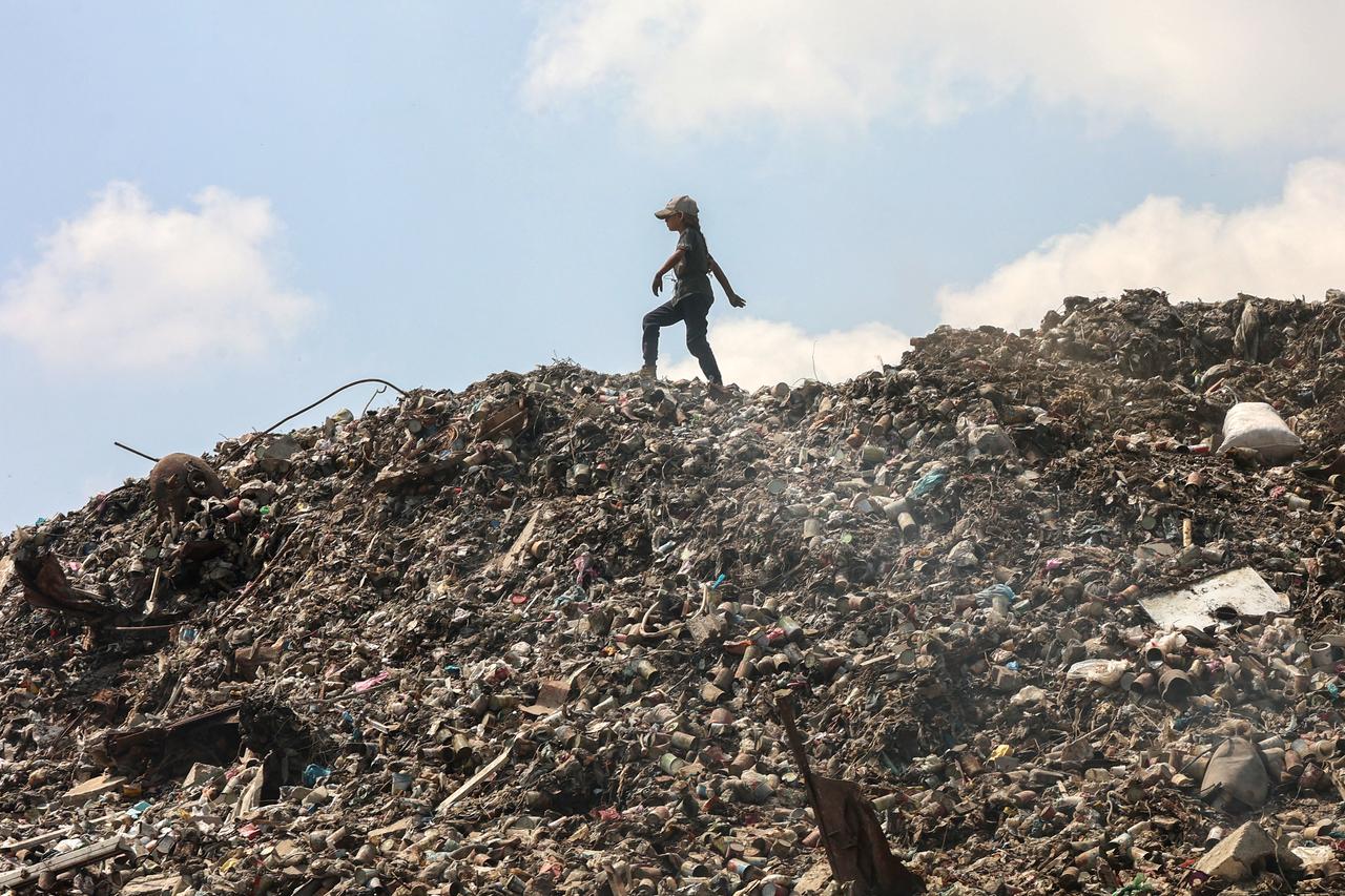 A Palestinian girl searches for things to salvage at a garbage waste dump in Gaza City on August 18, 2025. (AFP Photo)