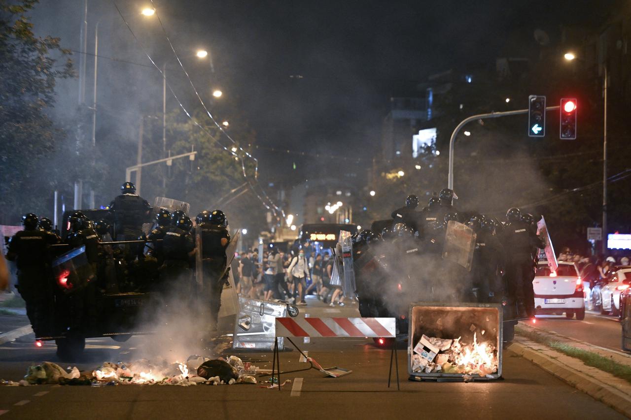 Serbian riot police officers travel on the back of a vehicle past burning garbage containers scattered along a road as the face protestors during ongoing anti-government protests in Belgrade, Serbia, August 18, 2025. (AFP Photo)