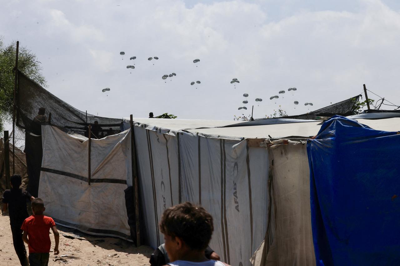Children watch as food parcels are airdropped in Rafah in the southern Gaza Strip, August 2, 2025. (AFP Photo)