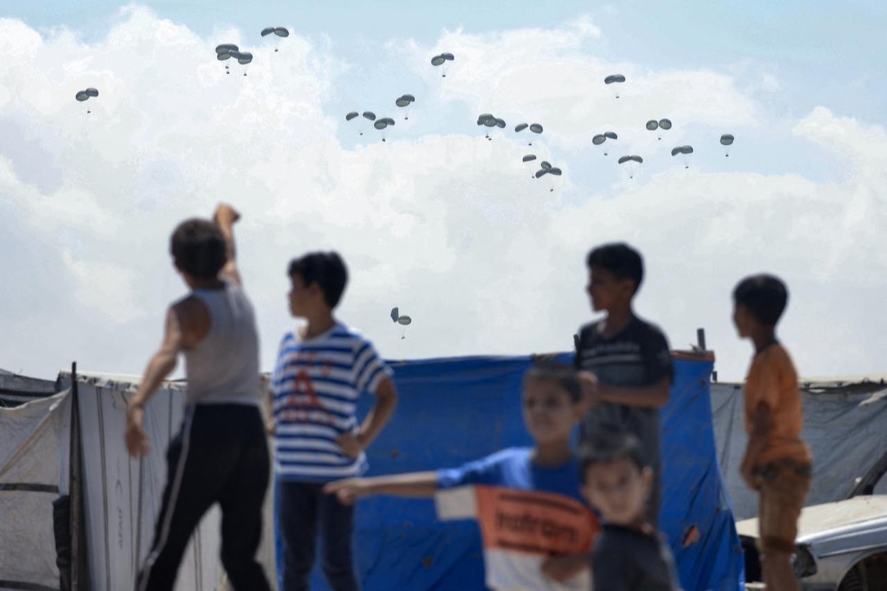 Children watch as food parcels are airdropped in Rafah in the southern Gaza Strip, August 2, 2025. (AFP Photo)