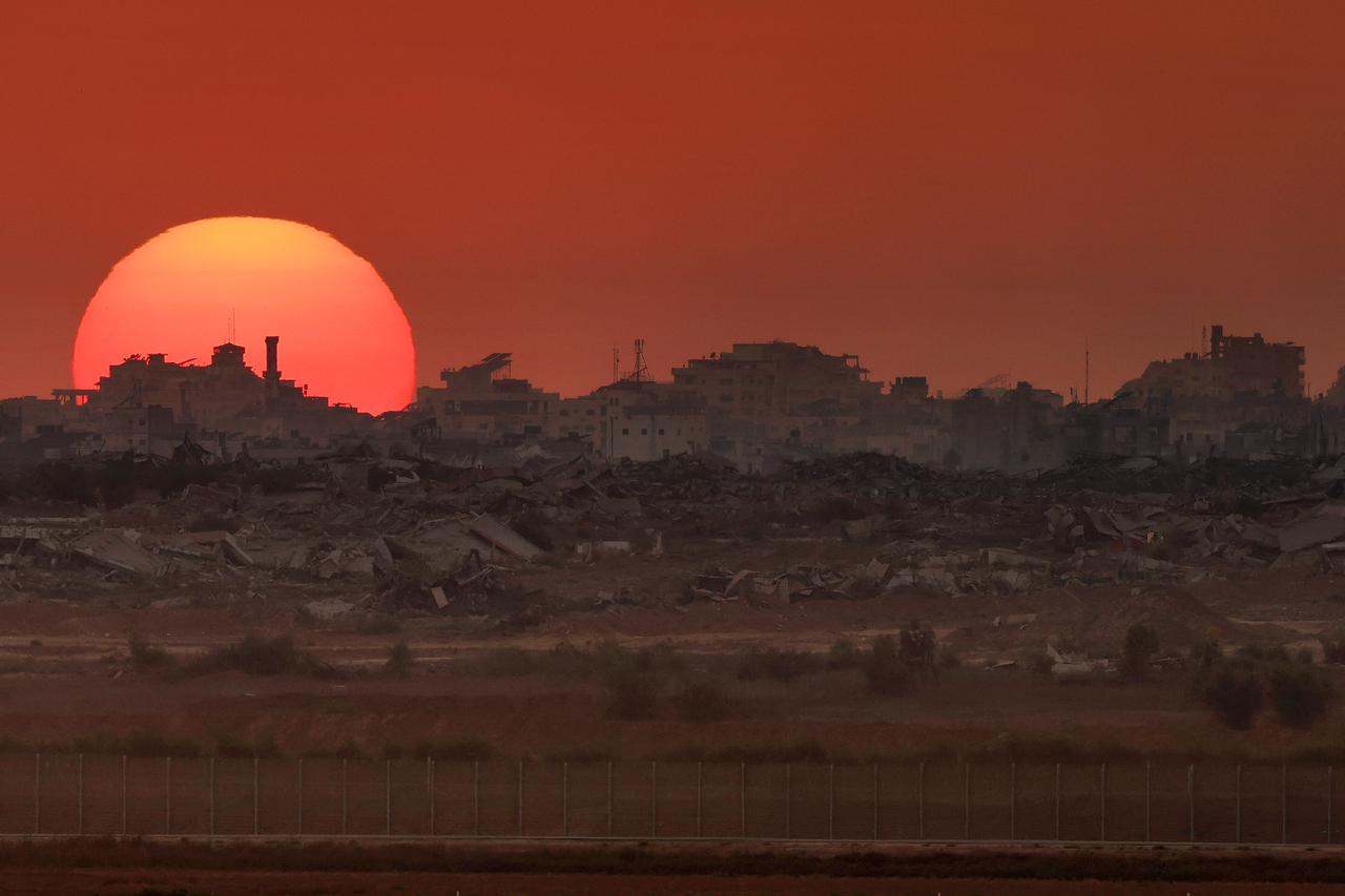 The sun setting behind destroyed buildings in the besieged Palestinian territory on August 19, 2025. (AFP Photo)