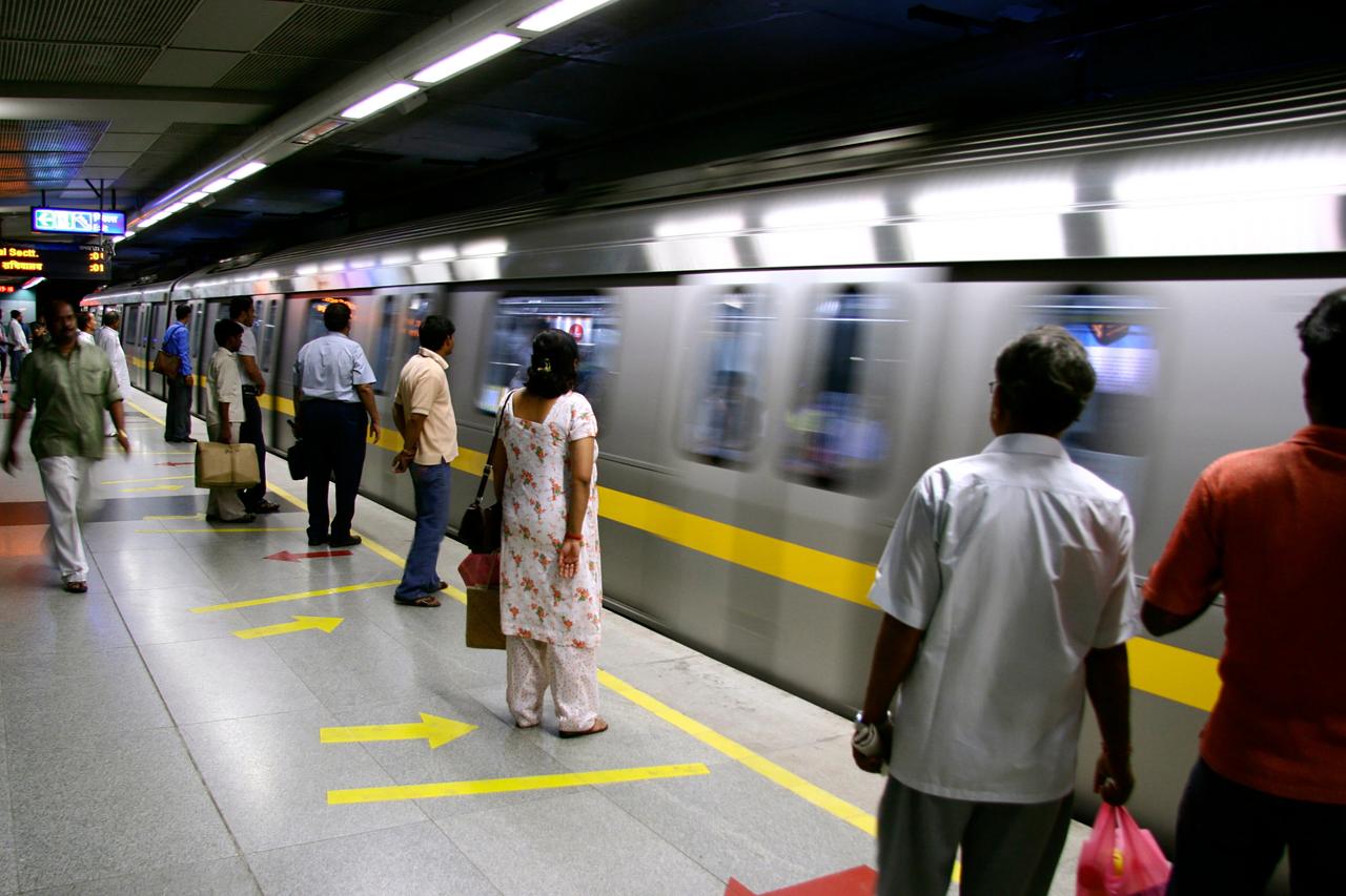 Passengers wait on a platform for an arriving metro train in Delhi, India. (Adobe Stock Photo)