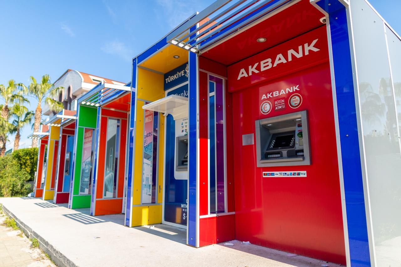 ATMs of several Turkish banks, including Akbank, stand side by side on a street. (Adobe Stock Photo)