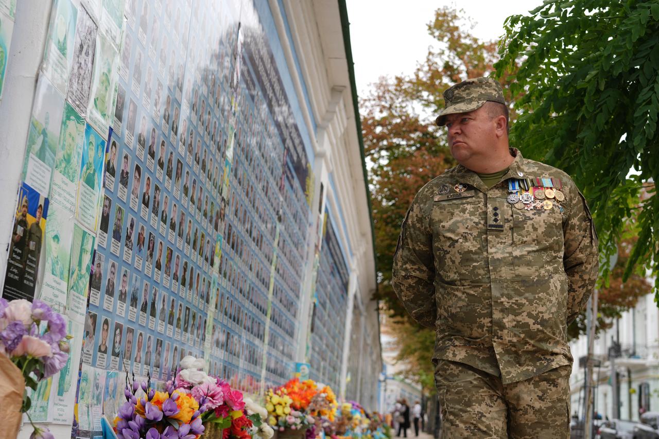 A serviceman looks at photographs of fallen comrades at the "Wall of Remembrance of the Fallen for Ukraine" on Ukraine's Independence Day in Kyiv on August 24, 2025. (AFP Photo)